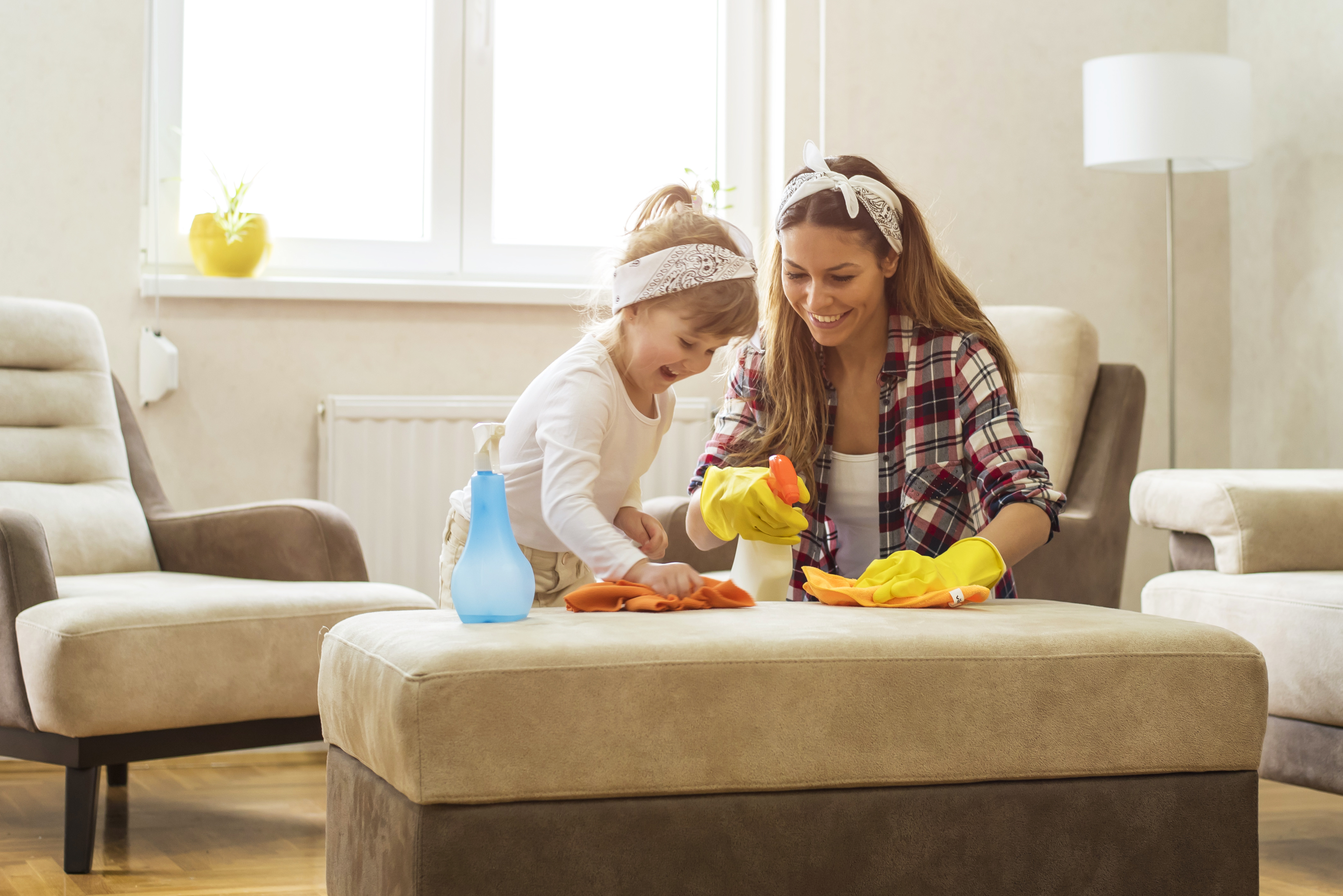 Child helping parent clean furniture