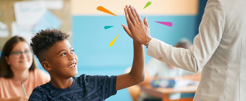 Student high-fiving teacher in classroom after doing good job Student high-fiving teacher in classroom after doing good job