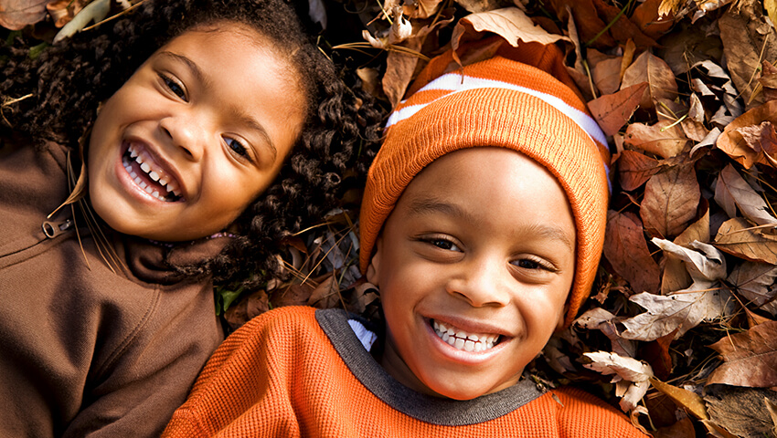 Small school children playing in pile of leaves