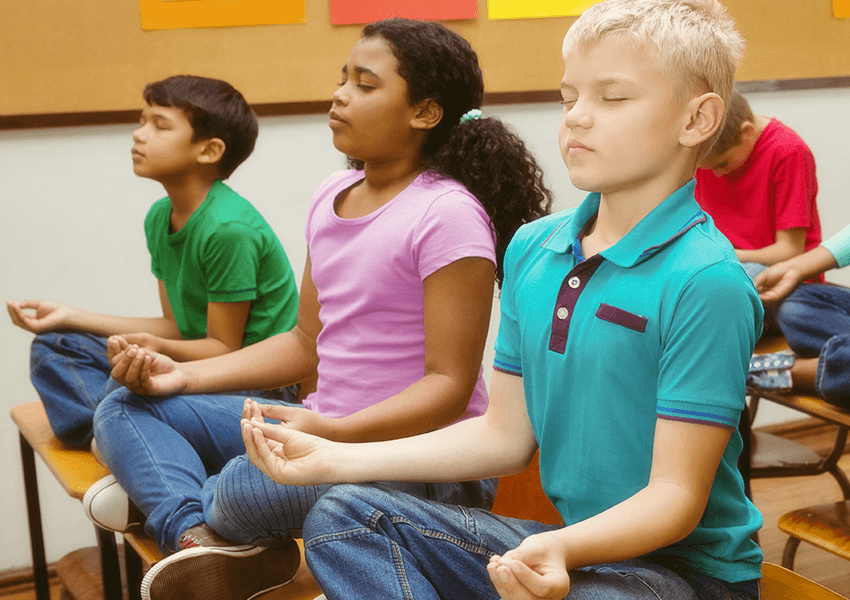 Students practicing mindfulness by meditating in the classroom