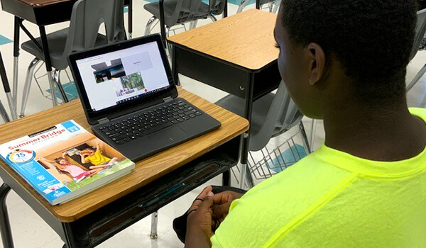 Child using laptop to help him with Summer Bridge workbook activity 