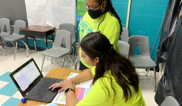 Teacher helping student on Summer Bridge Workbook activity