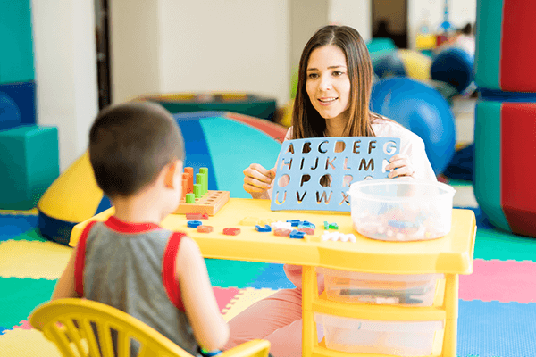 Teacher working with alphabet manipulative in classroom with student