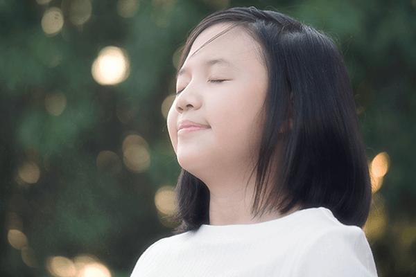 Grade school female child practicing muscle relaxation via meditating