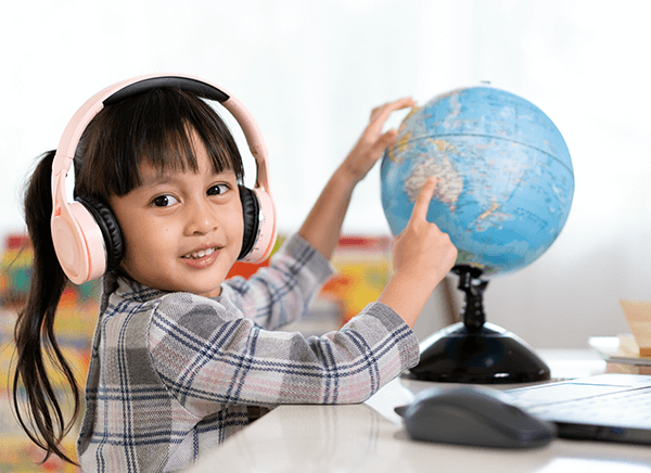Student in bilingual class with headphones on point at location on globe 