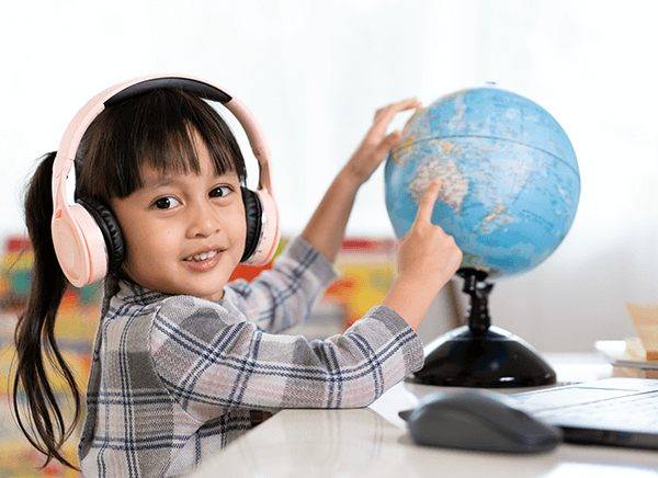 Student in bilingual class with headphones on point at location on globe Student in bilingual class with headphones on point at location on globe
