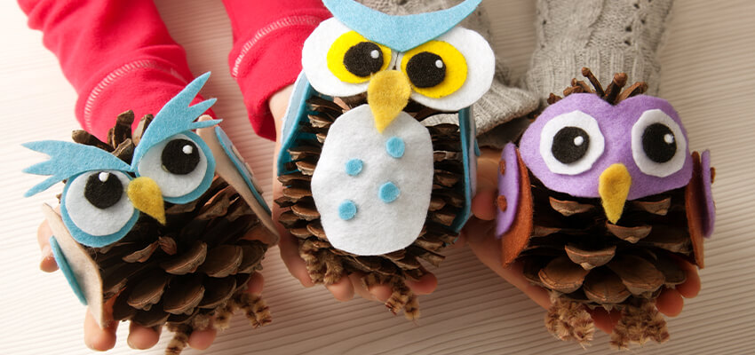 Children holding owls made out of acorns for fall activity 