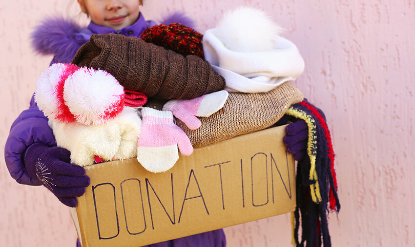 Child holding donation box filled with clothes