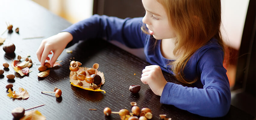 Homeschool child making a fall craft out of leaves at kitchen table