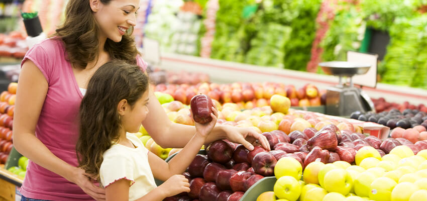 Mother and daughter viewing fresh produce at grocery store